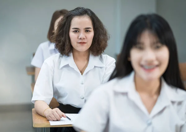 在课堂上写作和学习的快乐的亚洲女大学生的画像 在教室里学习的有选择性的 富家子弟 — 图库照片