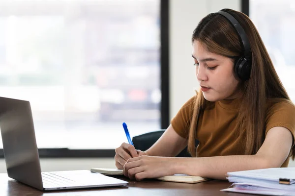 Joven Estudiante Asiática Lleva Auriculares Inalámbricos Concentrados Escribir Cuaderno Para —  Fotos de Stock