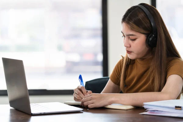 Joven Estudiante Asiática Lleva Auriculares Inalámbricos Concentrados Escribir Cuaderno Para —  Fotos de Stock