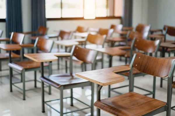 Empty university classroom with many wooden chairs. Wooden chairs well arranged in college classroom. Empty classroom with vintage tone wooden chairs. Back to school concept.