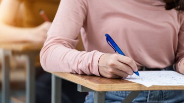Sınavların cevaplarını sınıftaki cevap kağıdına yazan genç üniversite öğrencilerini kapatın..