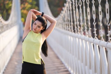 Spor kıyafetli genç bir Asyalı atlet sabah spor öncesi antrenman, koşu ve spor antrenmanlarından önce ısınma hareketleri yapıyor. Spor ve eğlence.