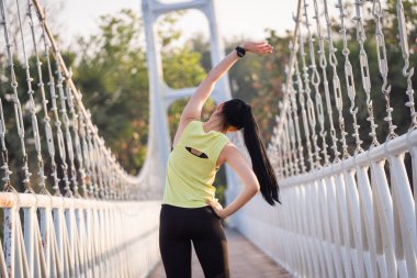 Spor kıyafetli genç bir Asyalı atlet sabah spor öncesi antrenman, koşu ve spor antrenmanlarından önce ısınma hareketleri yapıyor. Spor ve eğlence.