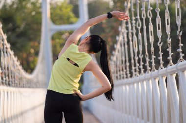 Spor kıyafetli genç bir Asyalı atlet sabah spor öncesi antrenman, koşu ve spor antrenmanlarından önce ısınma hareketleri yapıyor. Spor ve eğlence.