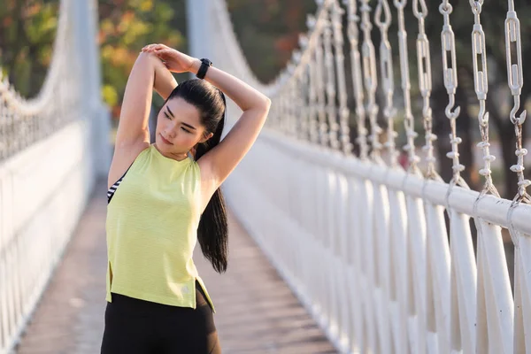 Spor kıyafetli genç bir Asyalı atlet sabah spor öncesi antrenman, koşu ve spor antrenmanlarından önce ısınma hareketleri yapıyor. Spor ve eğlence.