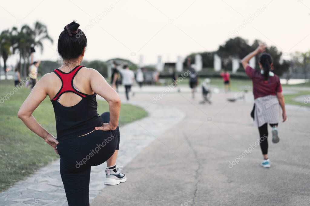 Rearview of matured healthy people doing aerobics dance in the city park in the evening after work to relax and get a healthy life. Sports and recreation
