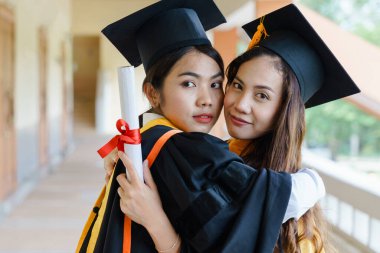 Mezuniyet elbisesi ve havan topu şapkasıyla mezun olan Asya Üniversitesi mezuniyet töreninde elde elde eğitim başarısını kutluyor. Mezuniyetleri kutlarım.