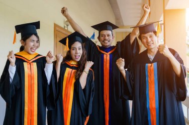 Üniversite mezuniyet elbisesi ve havan topu şapkasıyla mezuniyet töreninde elde eğitim başarısını kutlamak için diploma alır. Mezuniyetleri kutlarım.