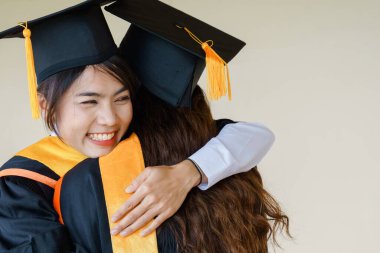 Üniversite mezuniyet elbisesi ve havan topu şapkasıyla mezuniyet töreninde elde eğitim başarısını kutlamak için diploma alır. Mezuniyetleri kutlarım.