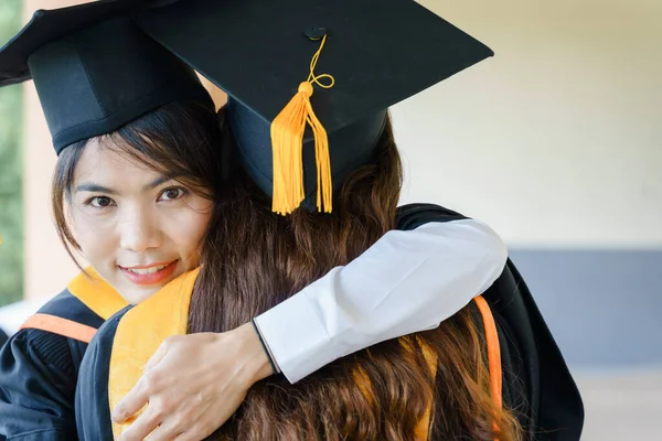 Üniversite mezuniyet elbisesi ve havan topu şapkasıyla mezuniyet töreninde elde eğitim başarısını kutlamak için diploma alır. Mezuniyetleri kutlarım.