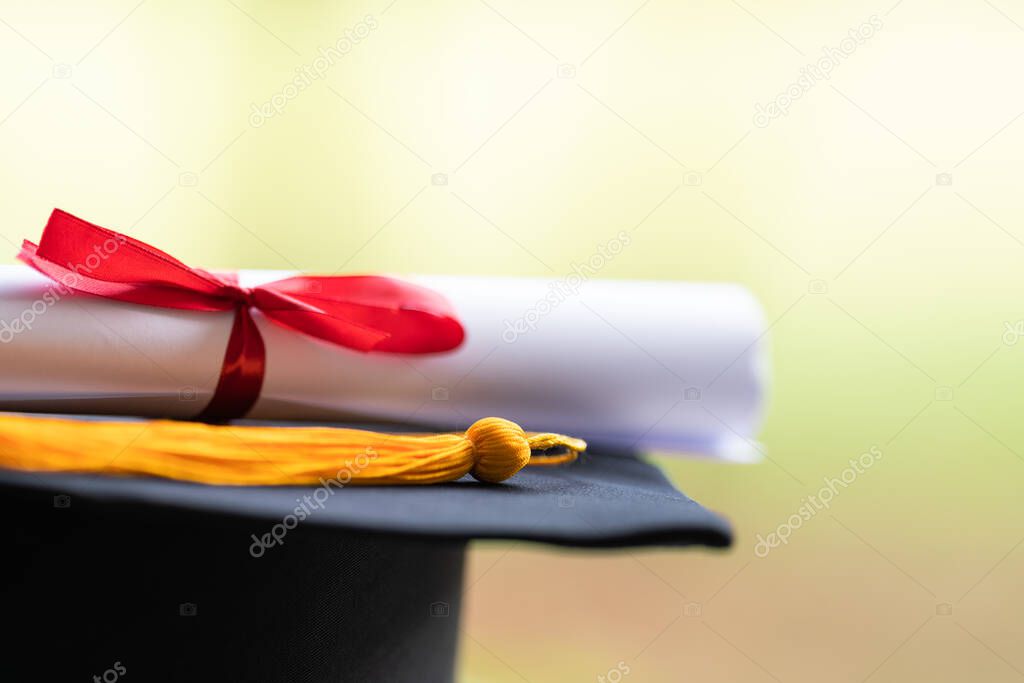 Close-up of a mortarboard and degree certificate put on table. Education stock photo
