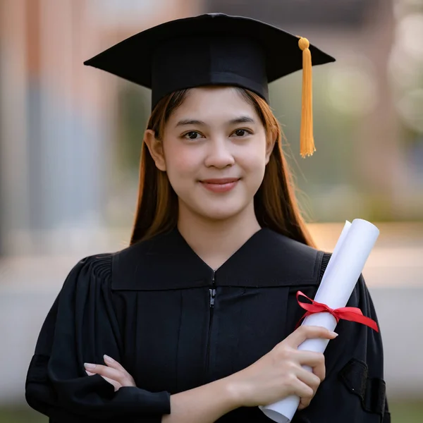 一名身穿毕业礼服的年轻快乐的亚洲女大学生在大学校园里获得了学位证书 以庆祝她的教育成就 教育库存照片 — 图库照片