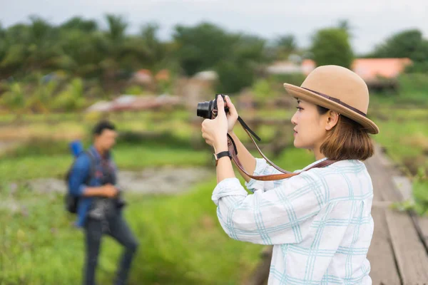 緑のフィールドでの夏休みの休暇中に風景写真を撮ることを楽しむ観光客の女性 リラックスしながら 自分自身と風景を撮影帽子のスタイリッシュな旅行者の女性 — ストック写真