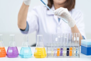 Modern bir laboratuvarda bilimsel deneyleri araştırmak, incelemek ve incelemek için plastik tüplerle çalışan genç bir kadın araştırmacı, doktor, bilim adamı veya laboratuvar asistanı. Eğitim stoku fotoğrafı