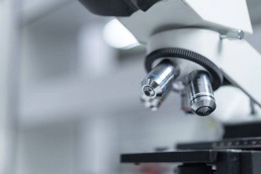 Bir mikroskobun yakın çekim ve seçici odak noktası, Sıvı ile tıbbi test tüpleri, ve diğer modern laboratuvar ekipmanları bir laboratuvar odasında. Eğitim stoku fotoğrafı