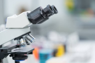 Bir mikroskobun yakın çekim ve seçici odak noktası, Sıvı ile tıbbi test tüpleri, ve diğer modern laboratuvar ekipmanları bir laboratuvar odasında. Eğitim stoku fotoğrafı