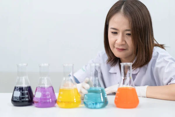 A young woman researcher, doctor, scientist, or laboratory assistant working with plastic medical tubes to research, examine scientific experiments in a modern laboratory. Education stock photo