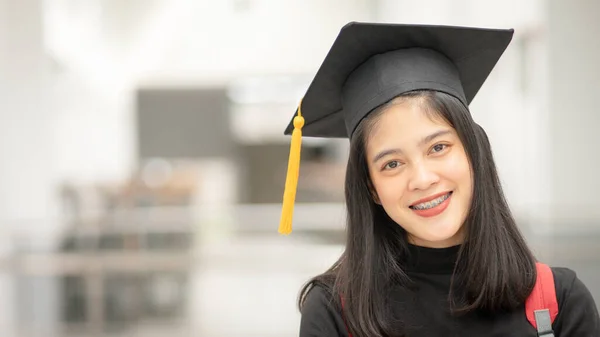 在大学校园里 年轻快乐的亚洲女大学生身着毕业礼服 头戴帽子 教育库存照片 — 图库照片