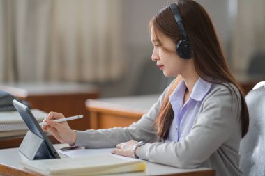Genç interaktif mutlu Asyalı genç kız üniversite öğrencisi derslerini internetten dijital bir tablette tek başına sunuyor. Eğitim stoku fotoğrafı