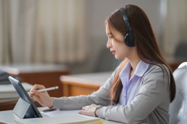 Genç interaktif mutlu Asyalı genç kız üniversite öğrencisi derslerini internetten dijital bir tablette tek başına sunuyor. Eğitim stoku fotoğrafı