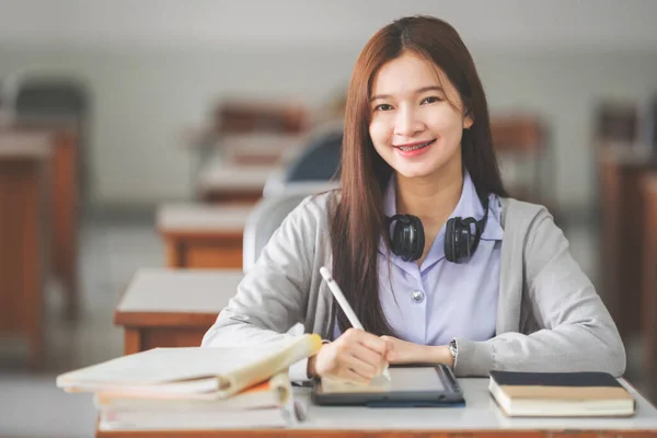 若い十代の女性のストックフォト大学の教室でデジタルタブレット上で勉強し 書き学生の制服でアジアの大学生 — ストック写真