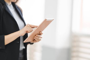 İş üniformalı bir iş kadınının iş yerinin dışında dijital tablet kullanırken yakın çekimi. İş yeri fotoğrafı