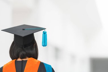 Mezuniyet elbisesi içinde, üniversite mezuniyet törenindeki başarısını göstermek ve kutlamak için havan topu sertifikası taşıyan bir üniversite mezununun yakın plan fotoğrafı. Eğitim stoku fotoğrafı