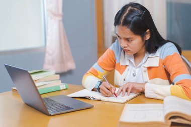 İnternette okuyan, kitap okuyan, üniversite kütüphanesinde dijital tablet ya da dizüstü bilgisayar kullanan stresli bir Asyalı üniversite öğrencisi.