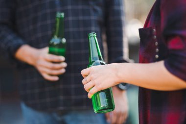 Yaz kampı partisinde elinde bira bardaklarıyla kutlama yapan insanların görüntüsü. Arkadaşlar kamp yaparken bir şişe bira içiyorlar.