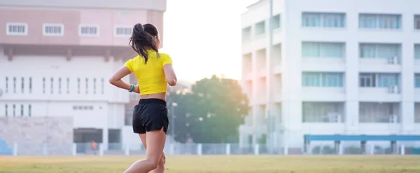 フィットネスと健康的なライフスタイルを維持するために 若いアジアの女性アスリートランナーが晴れた朝に市内のスタジアムでランニングコースをジョギングしています 若いフィットネス女性は陸上競技場で走ります スポーツとレクリエーション — ストック写真