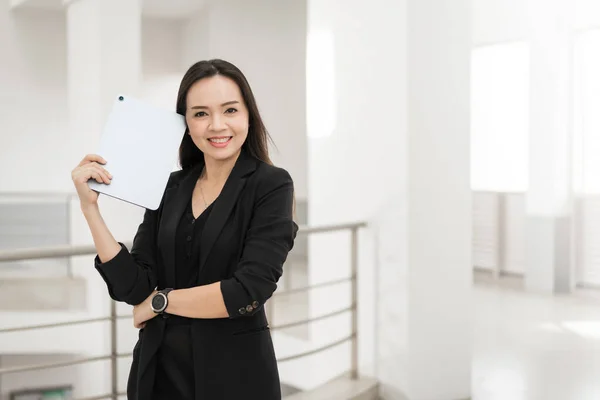 オフィスビル内に設置されたデジタルタブレットを活用し ビジネス志向のコンセプトを表現したブラックビジネススーツ姿のアジア人ビジネスマンの自信作 — ストック写真