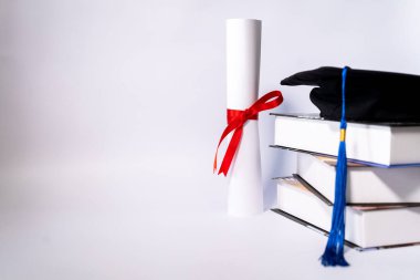 Mezuniyet havan ve diploma sertifikasının resmi beyaz zemin üzerinde izole edilmiş ve metin eklemek için negatif fotokopi alanı var. Mezuniyet şapkası. Masada beyaz arka plan var.