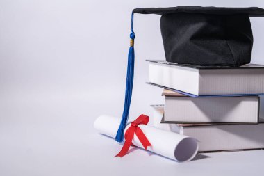 Mezuniyet havan ve diploma sertifikasının resmi beyaz zemin üzerinde izole edilmiş ve metin eklemek için negatif fotokopi alanı var. Mezuniyet şapkası. Masada beyaz arka plan var.