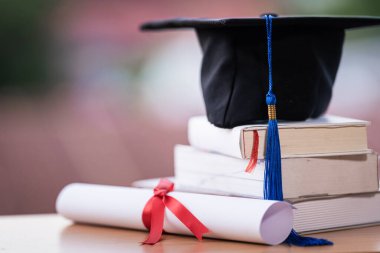 Mezuniyet şapkası havan tahtasının kesilmiş fotoğrafı ve diploma sertifikası masanın üzerinde.