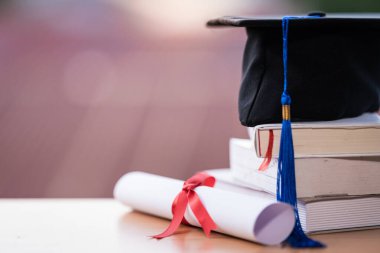 Mezuniyet şapkası havan tahtasının kesilmiş fotoğrafı ve diploma sertifikası masanın üzerinde.
