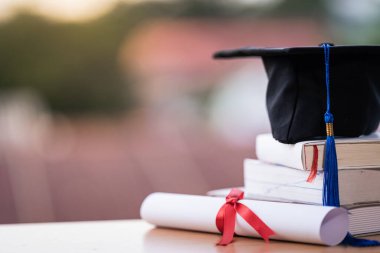 Mezuniyet şapkası havan tahtasının kesilmiş fotoğrafı ve diploma sertifikası masanın üzerinde.