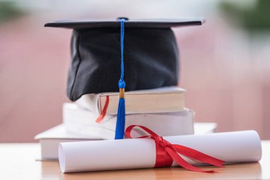 Mezuniyet şapkası havan tahtasının kesilmiş fotoğrafı ve diploma sertifikası masanın üzerinde.