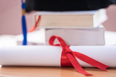 Mezuniyet şapkası havan tahtasının kesilmiş fotoğrafı ve diploma sertifikası masanın üzerinde.