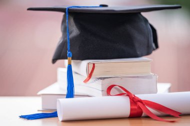 Mezuniyet şapkası havan tahtasının kesilmiş fotoğrafı ve diploma sertifikası masanın üzerinde.