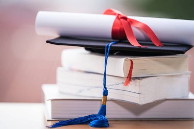 Mezuniyet şapkası havan tahtasının kesilmiş fotoğrafı ve diploma sertifikası masanın üzerinde.