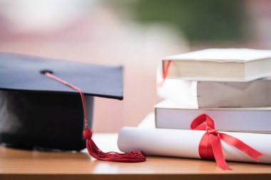 Mezuniyet şapkası havan tahtasının kesilmiş fotoğrafı ve diploma sertifikası masanın üzerinde.