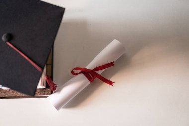 Mezuniyet şapkası ya da havan topu ve diploma sertifikası kağıdı bir yığın kitabın üzerine kırmızı kurdele bağlanmış boş bir boşluk ile vintage efekt için vignette ile biraz az doymuş