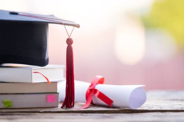 Mezuniyet şapkasının veya havan tahtasının ve diploma diplomasının masadaki seçici odak noktasını kapat