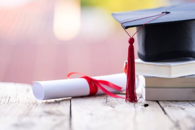 Mezuniyet şapkasının veya havan tahtasının ve diploma diplomasının masadaki seçici odak noktasını kapat