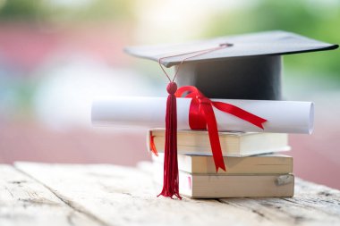 Mezuniyet şapkasının veya havan tahtasının ve diploma diplomasının masadaki seçici odak noktasını kapat