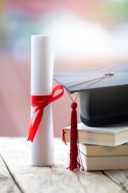 Mezuniyet şapkasının veya havan tahtasının ve diploma diplomasının masadaki seçici odak noktasını kapat