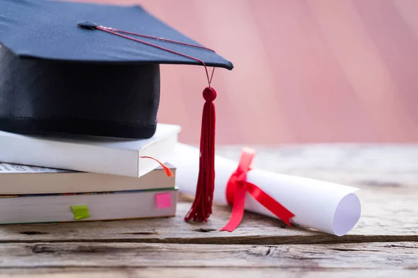 Mezuniyet şapkasının veya havan tahtasının ve diploma diplomasının masadaki seçici odak noktasını kapat