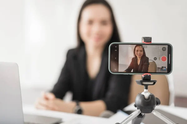 Yetişkin Asyalı kadın kolej öğretmeni evdeki öğrencilere video konferansı aracılığıyla ders veriyor. Gülümseyen Asyalı bayan öğretmen öğrencilerle video görüşmesi yapıyor..