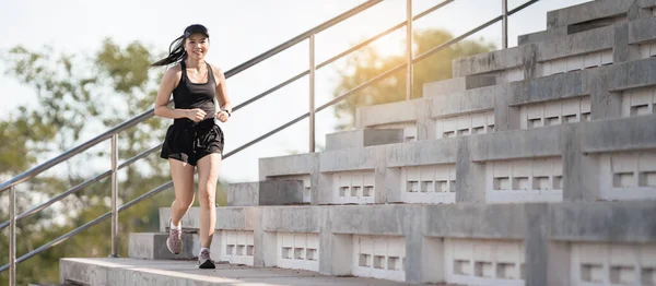 健康的な大人のアジアの女性は 体を強化するために市のスタジアムの具体的な階段で実行されます — ストック写真