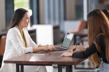 Genç Asyalı üniversite öğrencileri projeyi tartışmak için bir öğretmen danışmanıyla ya da özel öğretmenle görüşüyor.